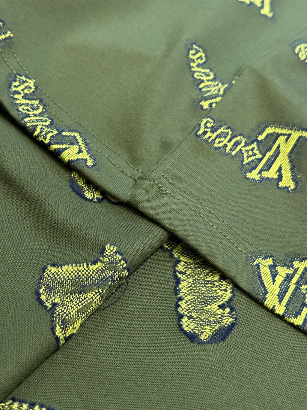 Green shirt with V-shaped seam and yellow LV-style logo embroidery