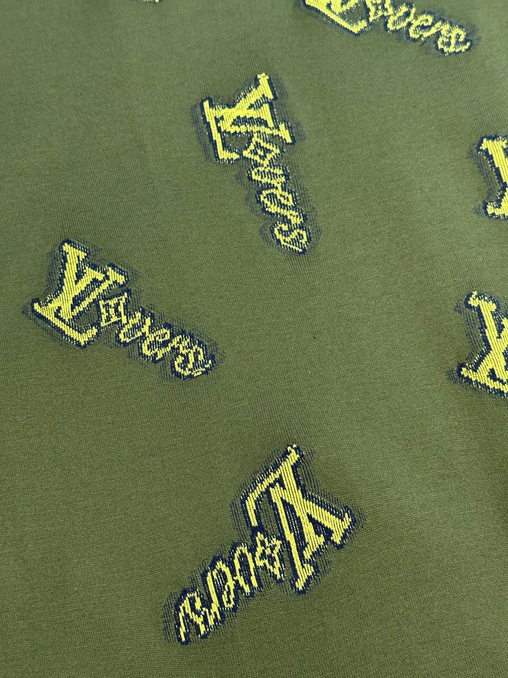 Green shirt fabric with yellow LV-style logo embroidery pattern