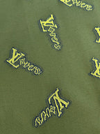 Green shirt fabric with yellow LV-style logo embroidery pattern