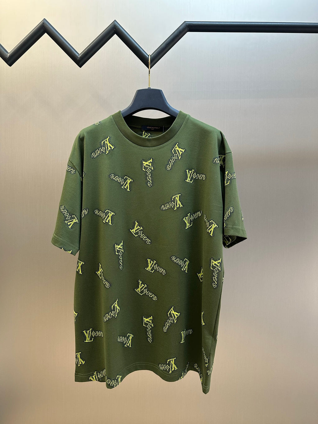 Green short-sleeve crewneck shirt with scattered yellow LV-style logo embroidery