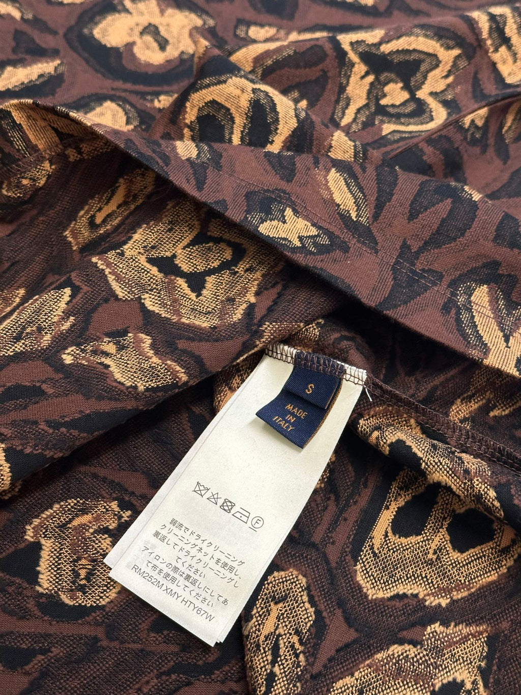 Louis Vuitton short-sleeve top inside seam label on dark brown and gold patterned fabric