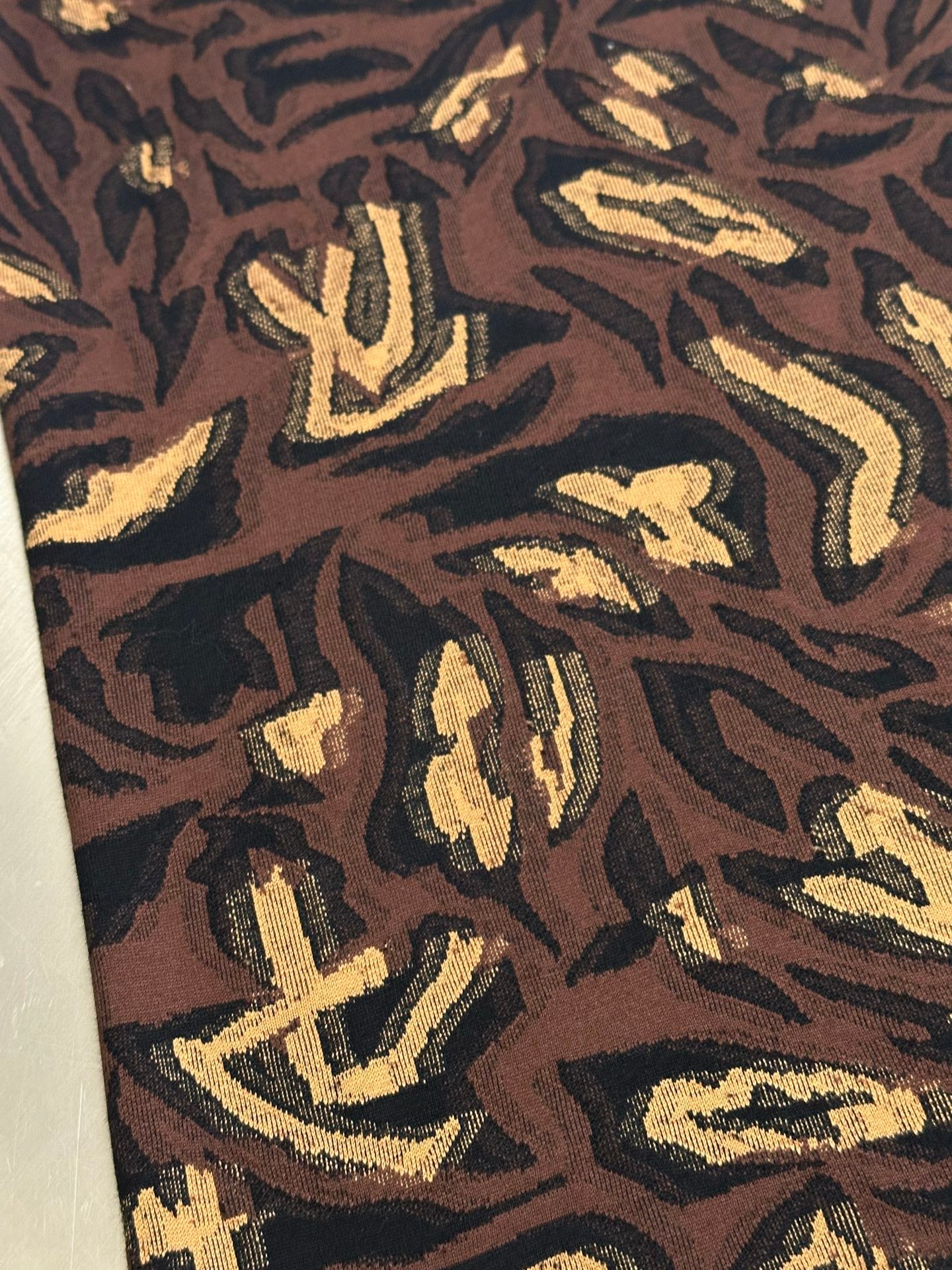 Louis Vuitton short-sleeve top fabric close-up with dark brown and gold motif pattern