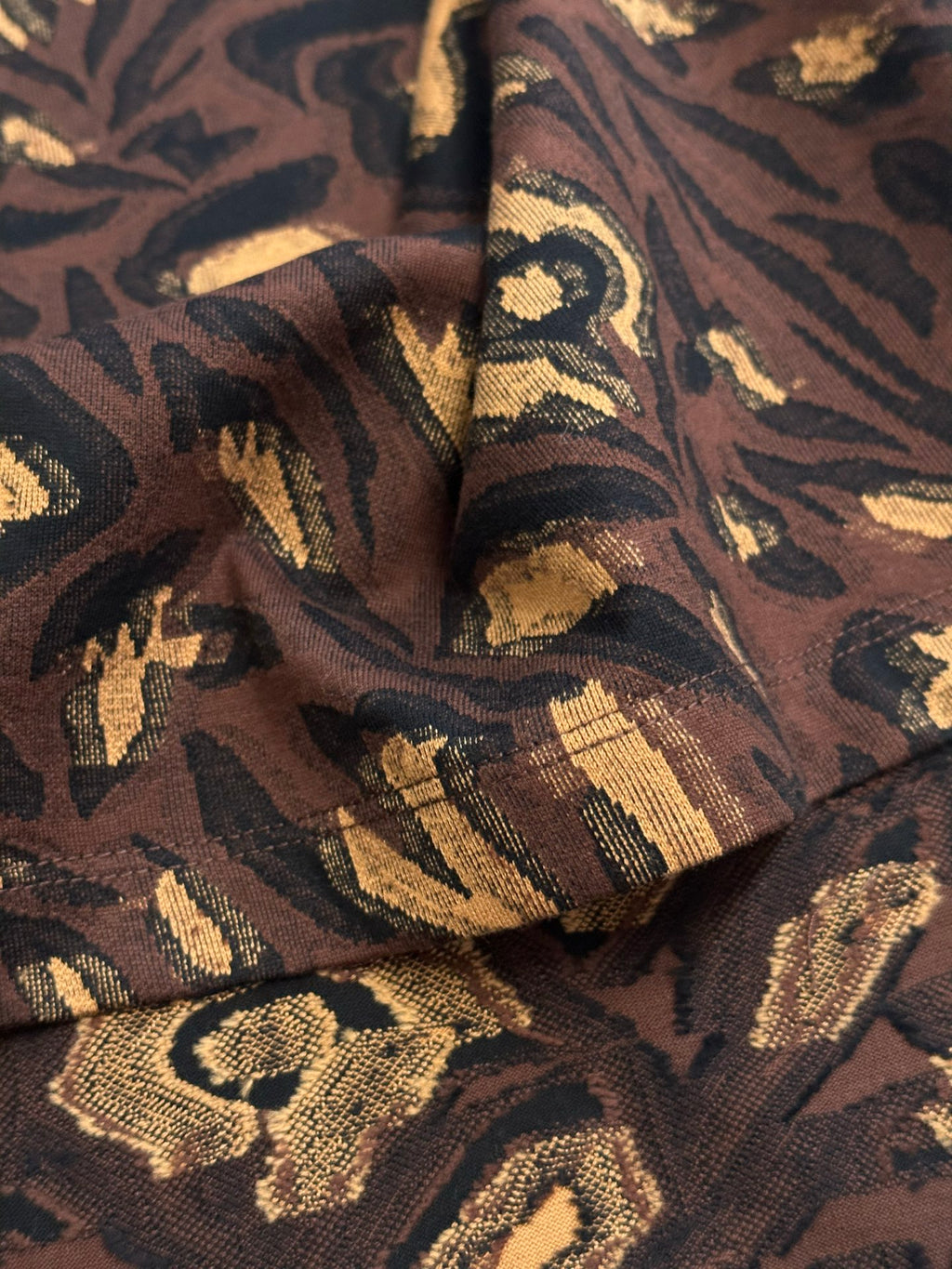 Louis Vuitton short-sleeve top fabric close-up with dark brown and gold woven texture