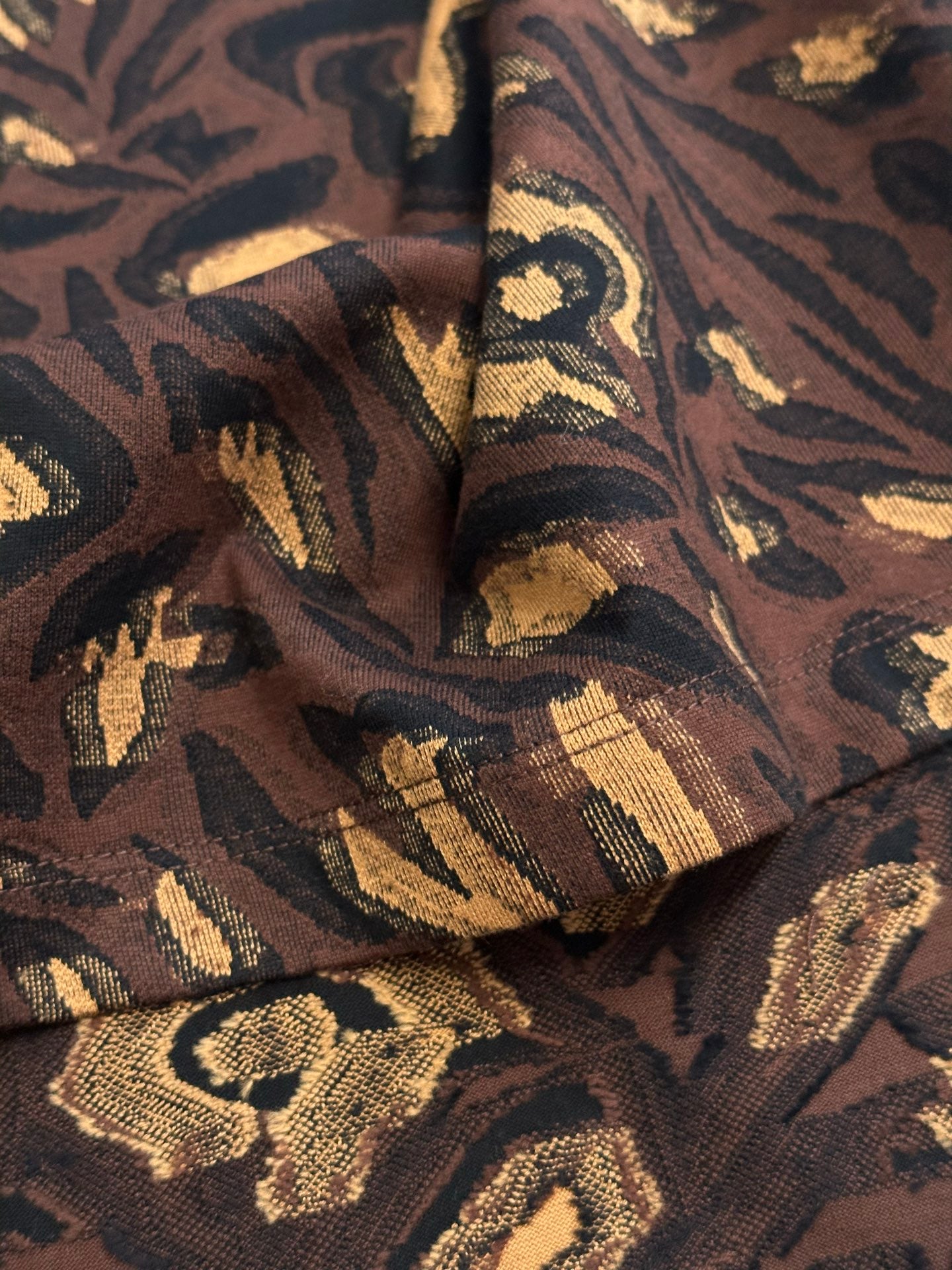 Louis Vuitton short-sleeve top fabric close-up with dark brown and gold woven texture
