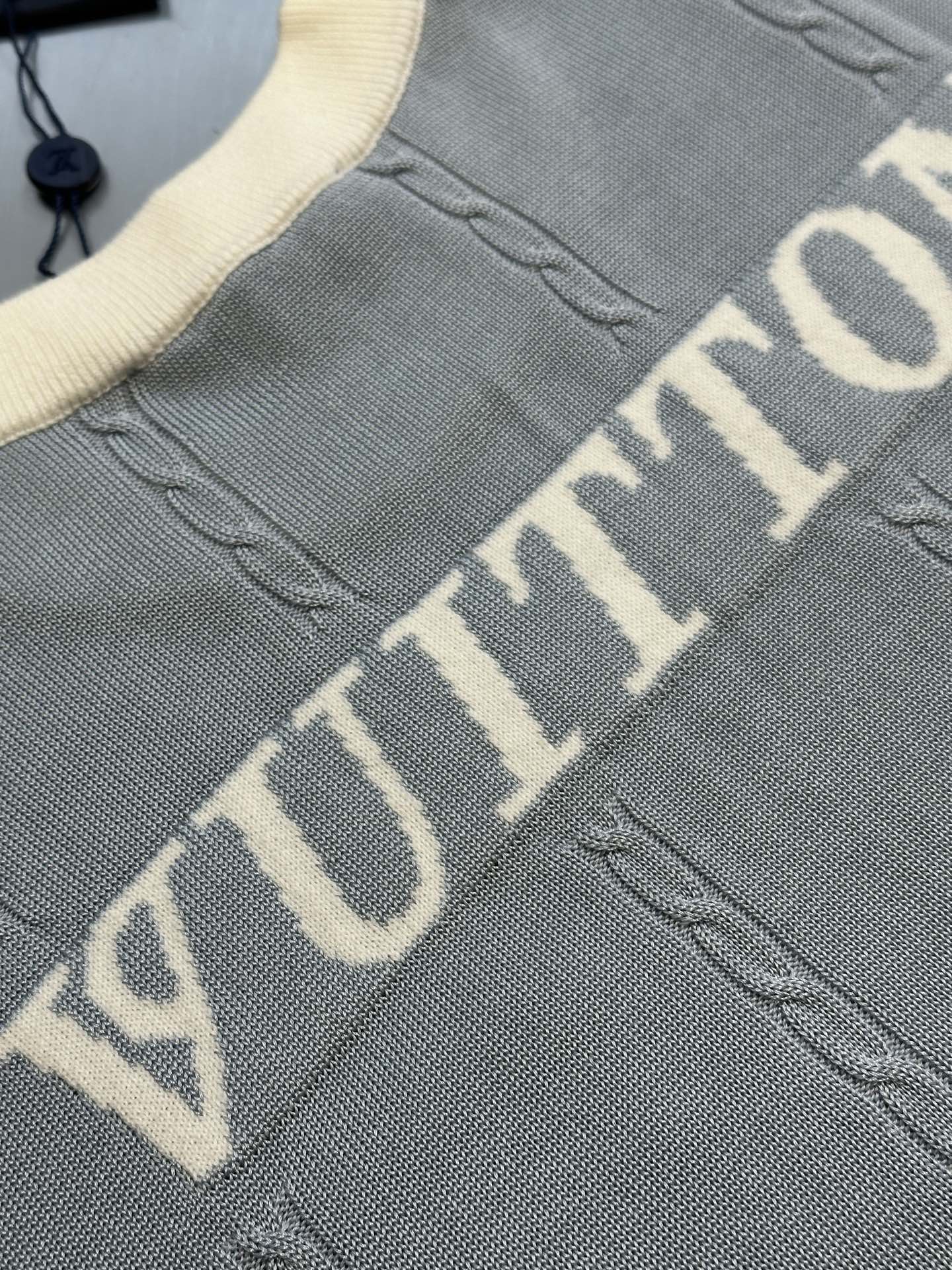 Light blue knit polo shirt with large 'VUITTON' lettering on front
