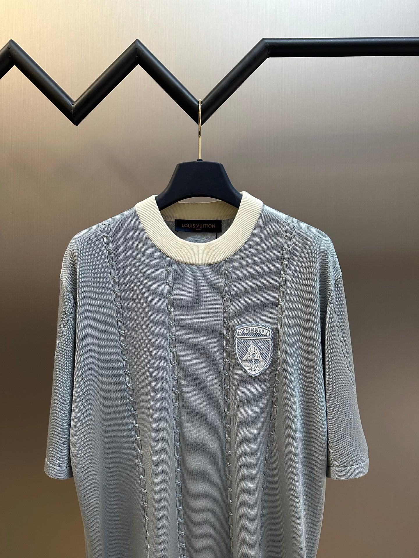 Light blue knit polo shirt with shield logo patch on chest