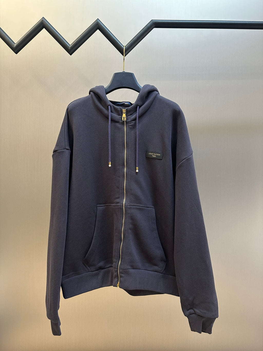 Dark navy zip-up hoodie with drawstring hood and gold zipper pull