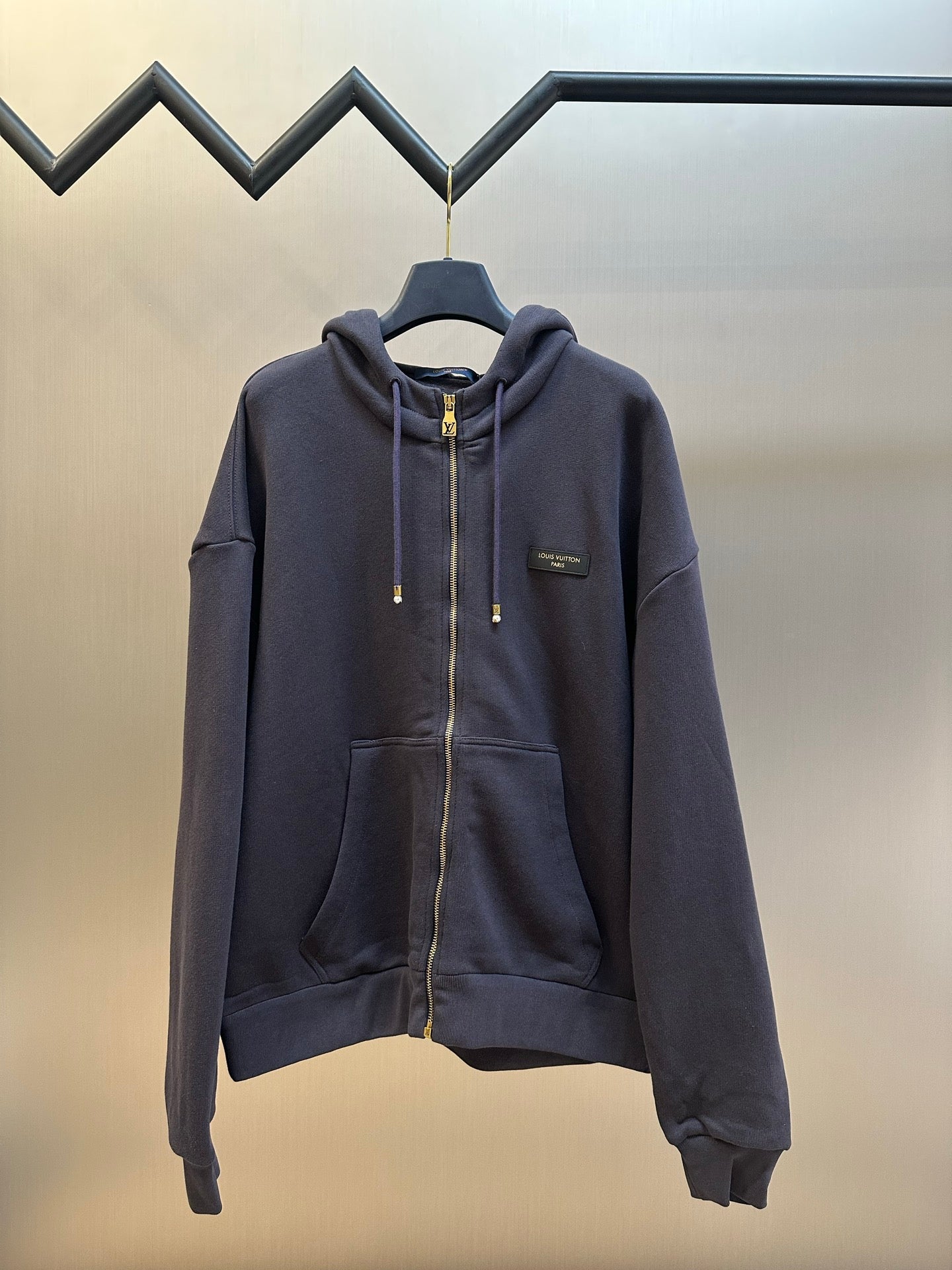 Dark navy zip-up hoodie with drawstring hood and gold zipper pull