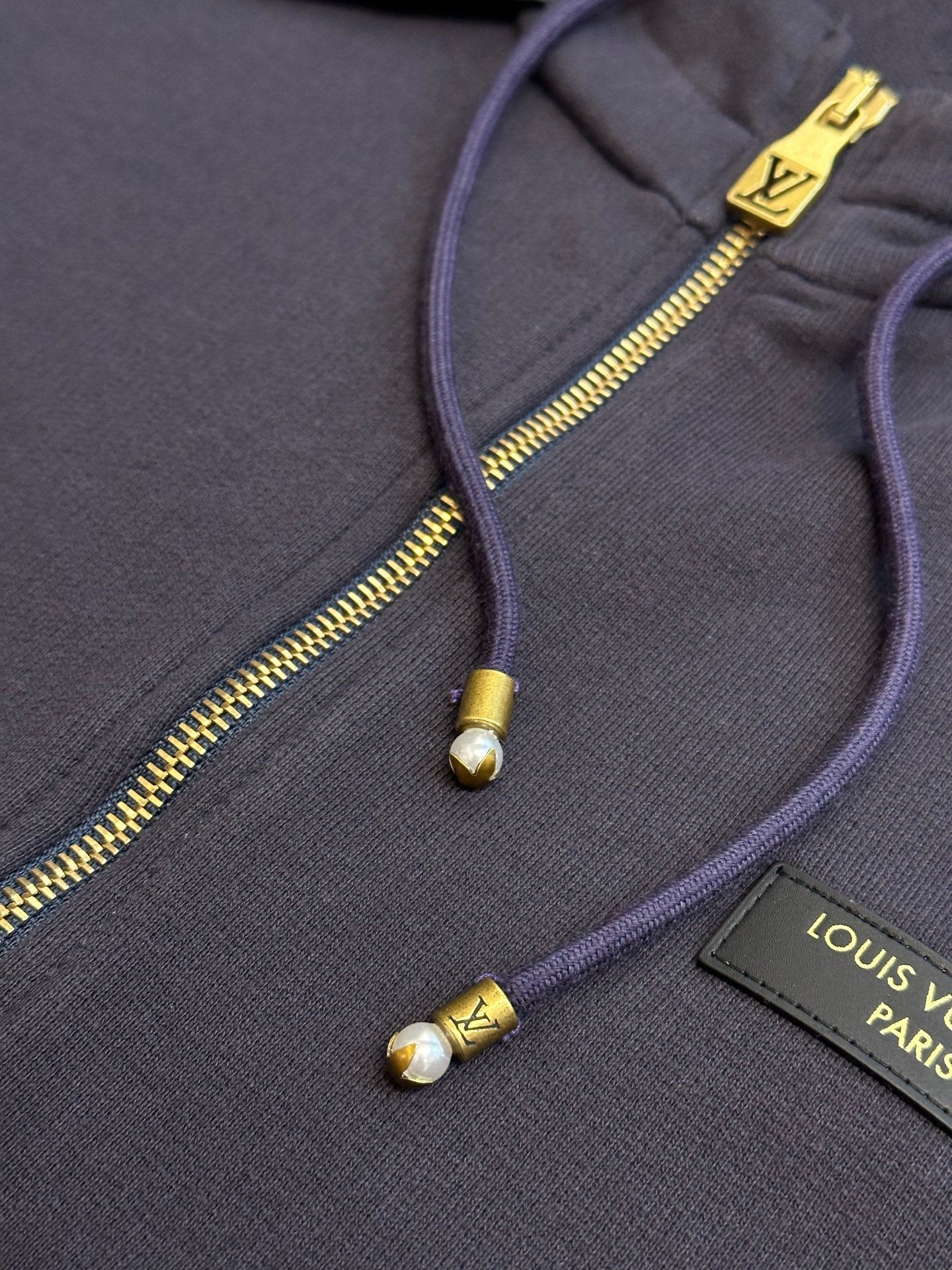 Dark navy hoodie with gold-tone zipper and drawstring aglets