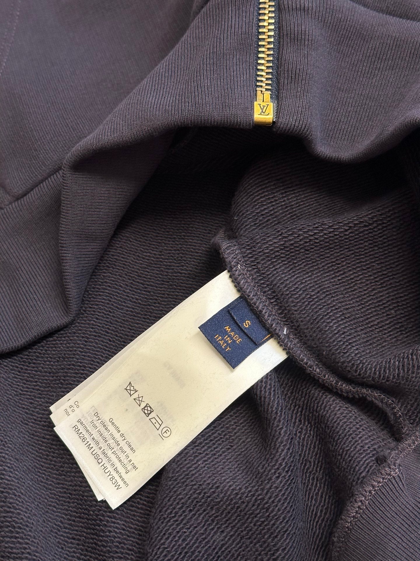 Dark navy hoodie with care and size tags near the zip opening