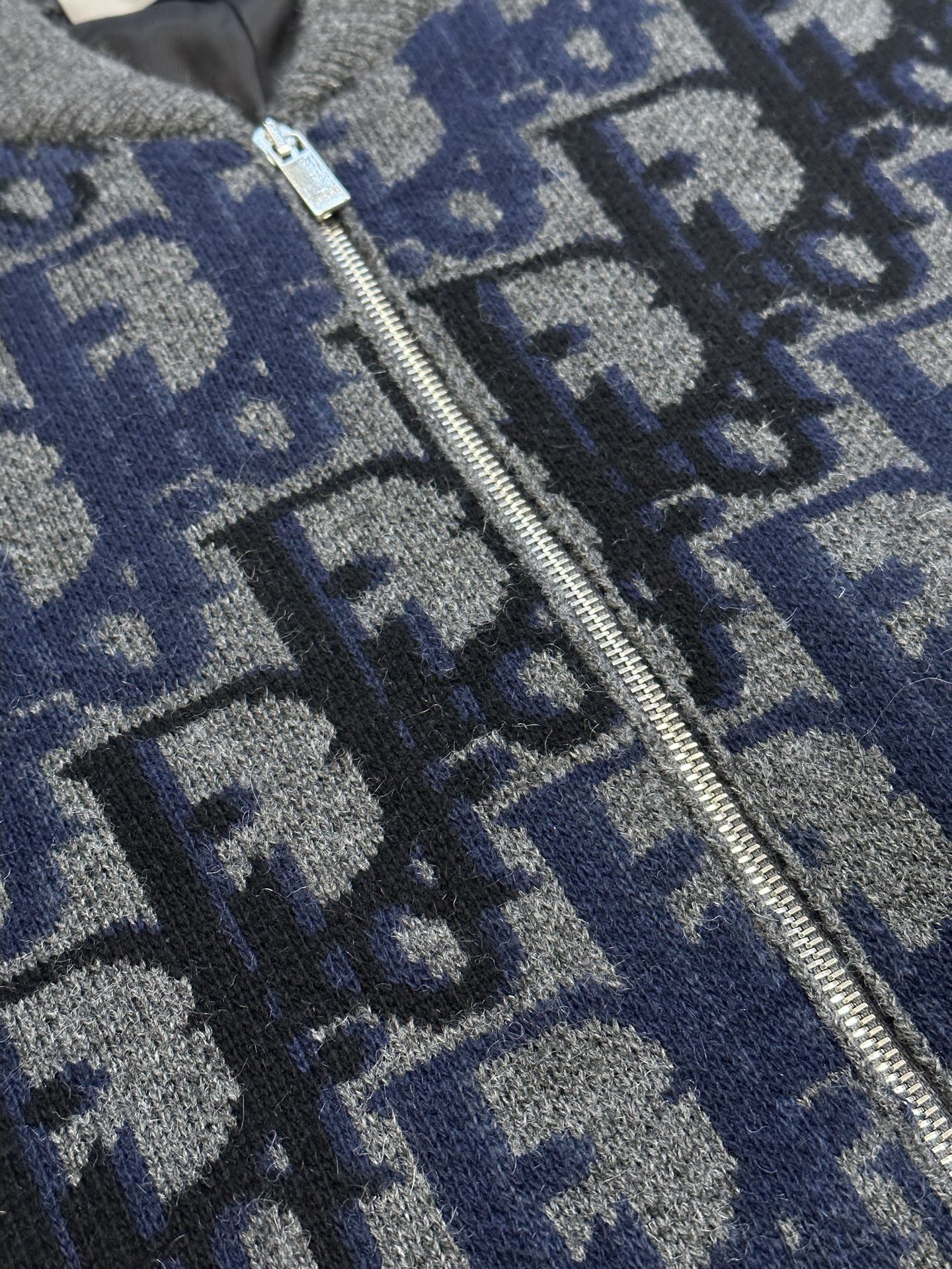 Logo knit zip jacket zipper close-up over blue-gray pattern