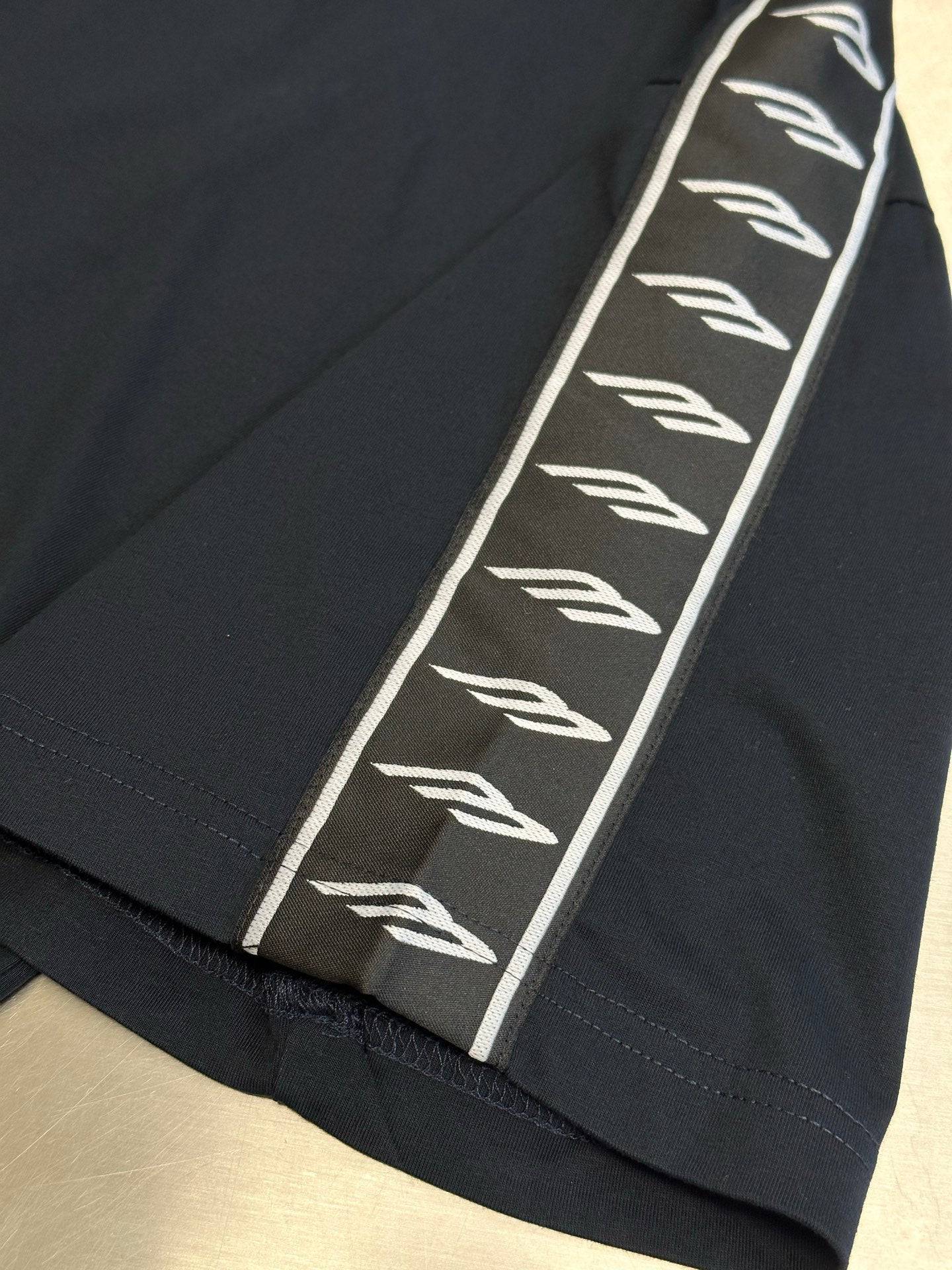 Close-up of dark navy T-shirt sleeve with white logo-tape stripe