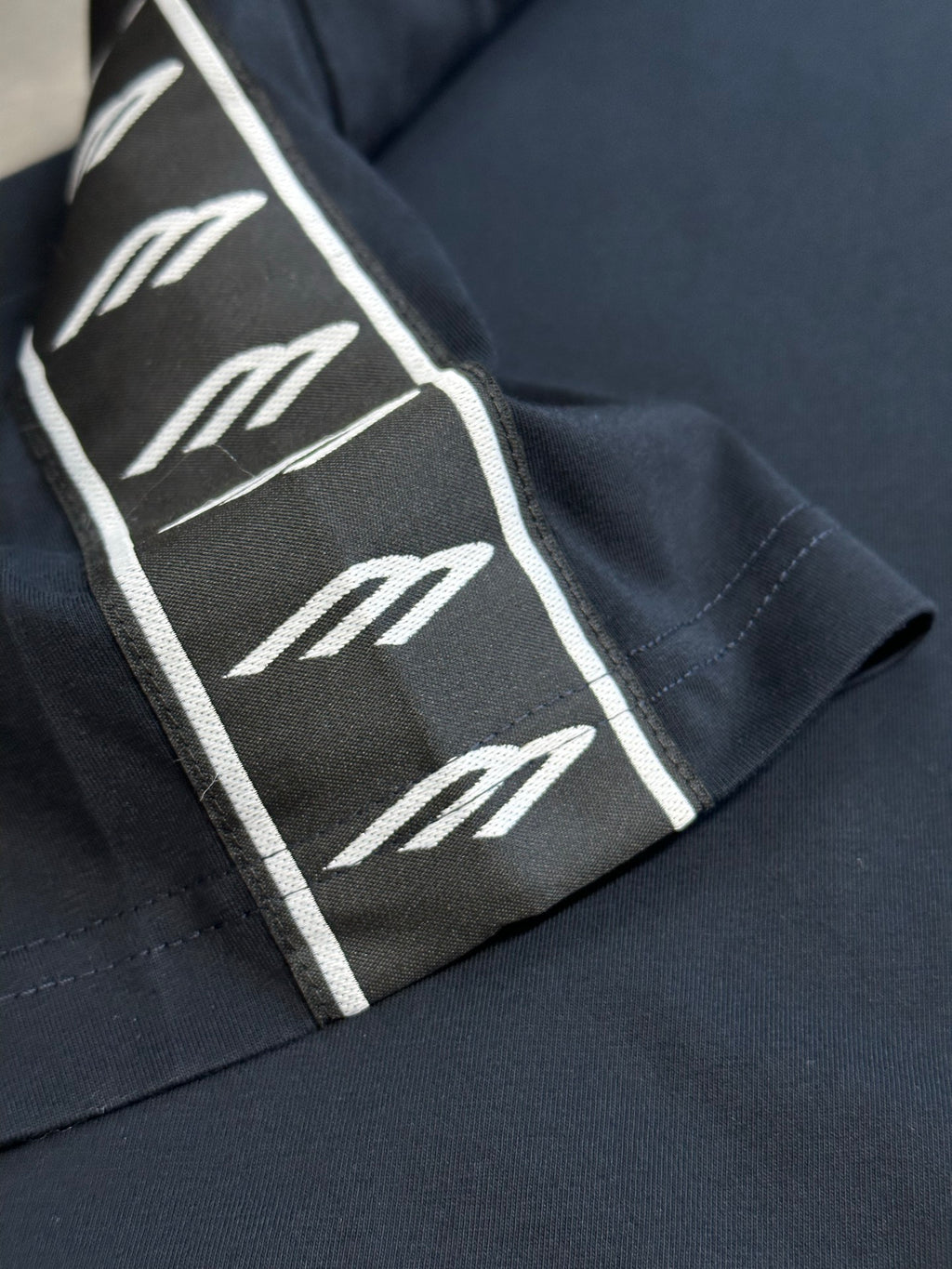 Close-up of sleeve logo-tape stripe on dark navy T-shirt