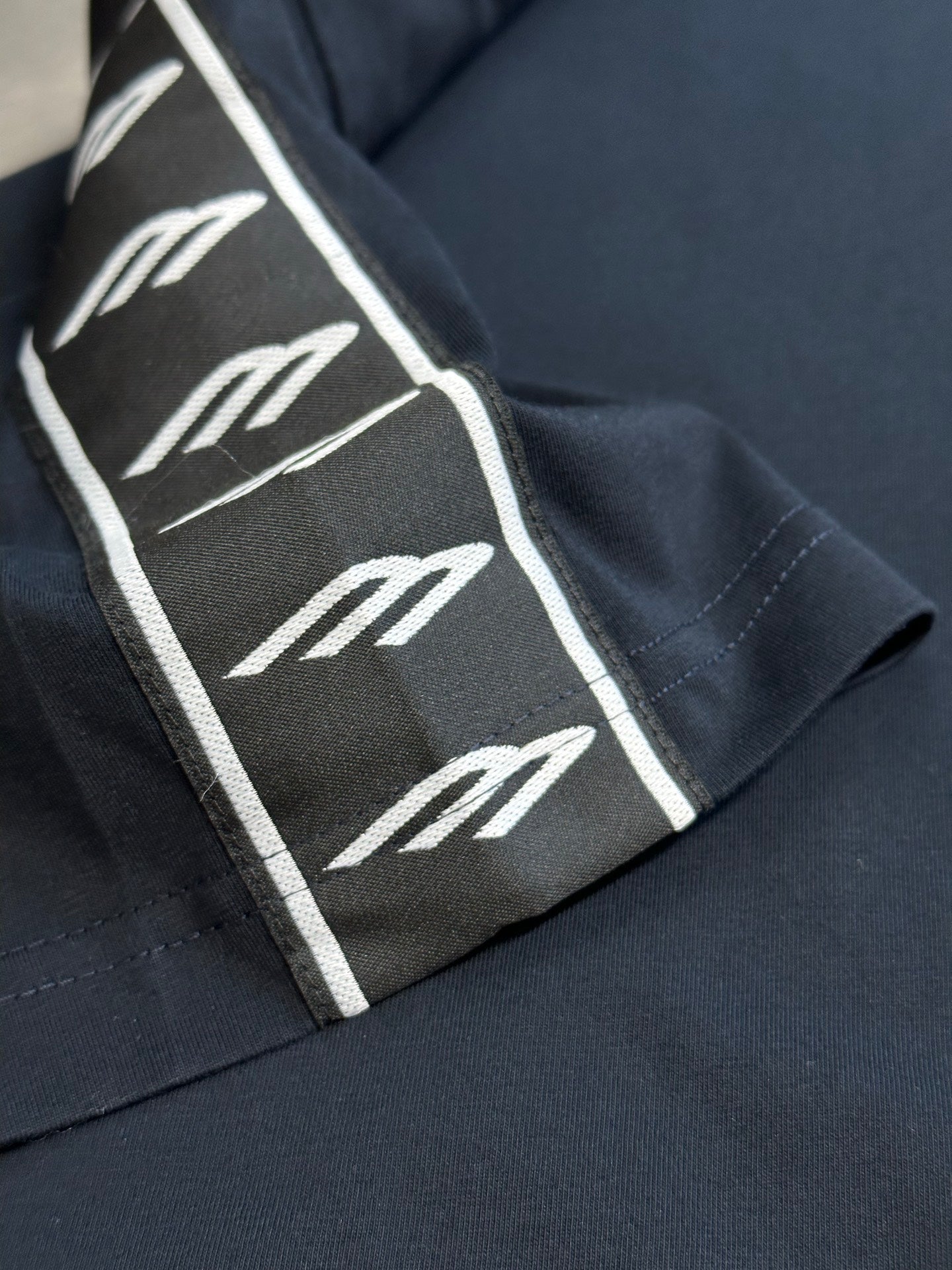 Close-up of sleeve logo-tape stripe on dark navy T-shirt