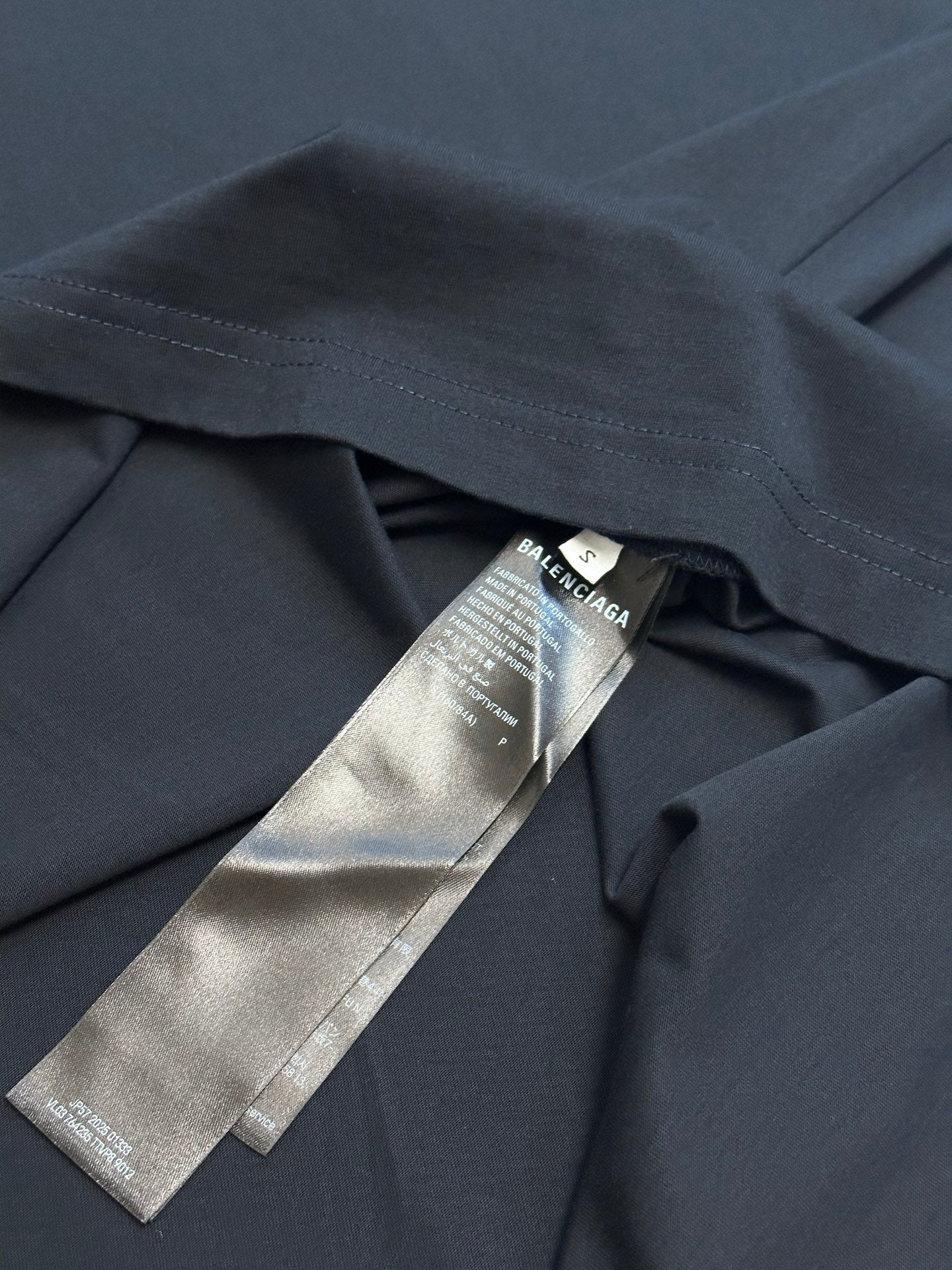 Dark navy T-shirt collar area with metallic hang tag