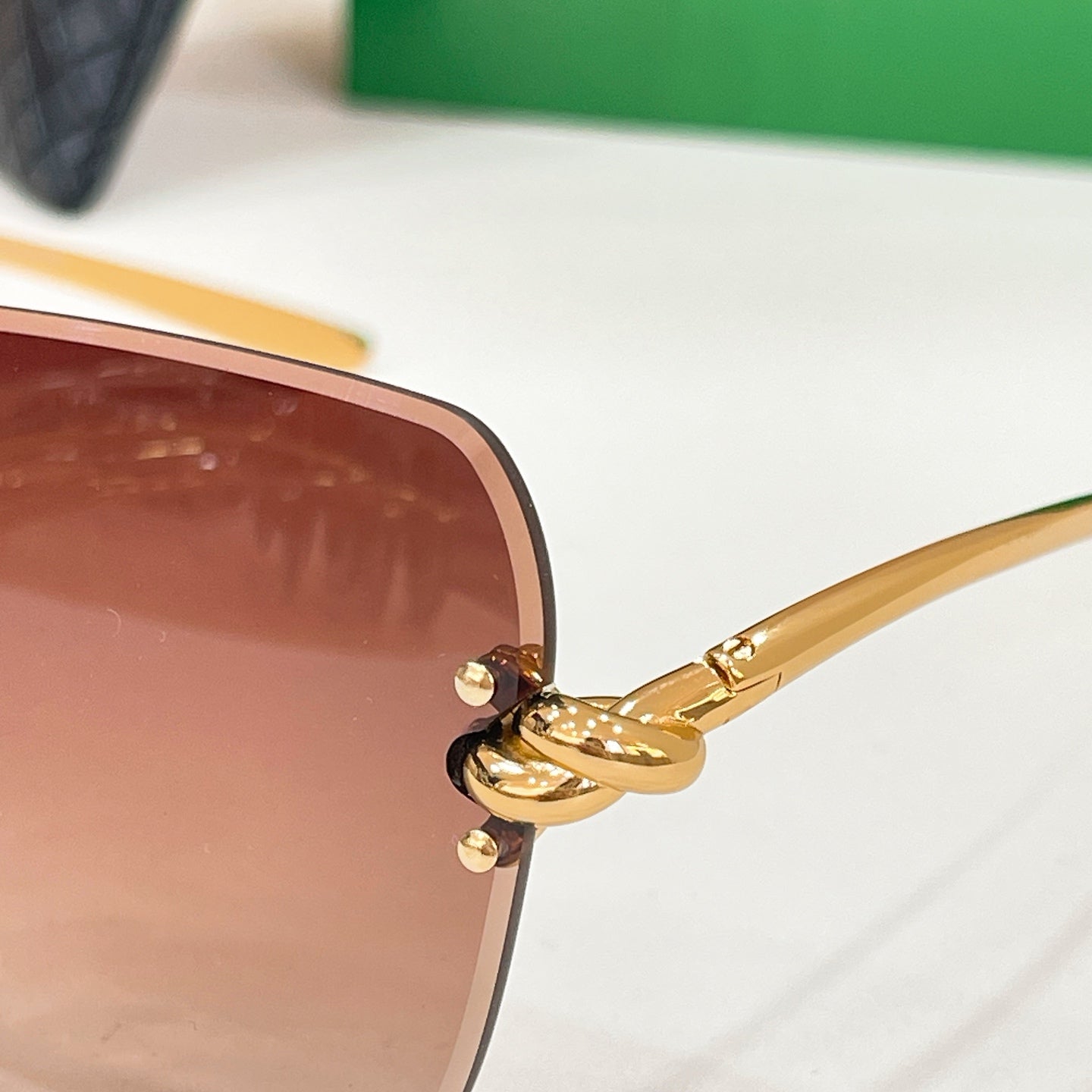 Bottega Veneta sunglasses close-up: brown tinted lens and gold-tone temples