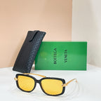Square sunglasses with black frame and warm yellow lenses, gold-tone hinge details