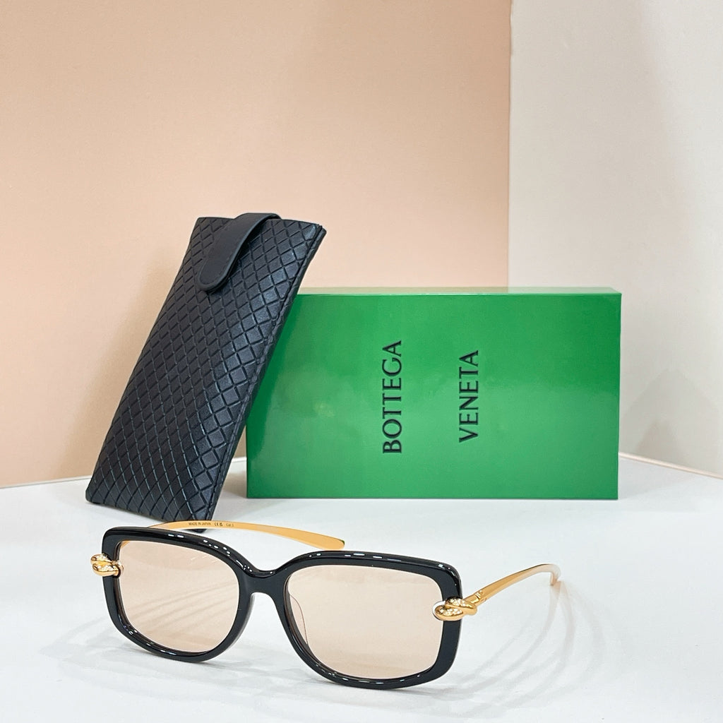 Square sunglasses with black frame and light/clear lenses, gold-tone hinge details
