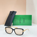 Square sunglasses with black frame and light/clear lenses, gold-tone hinge details