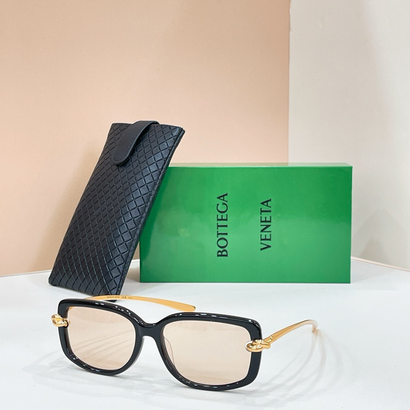 Square sunglasses with black frame and light/clear lenses, gold-tone hinge details