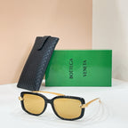 Square sunglasses with black frame and amber/yellow lenses, gold-tone bridge details