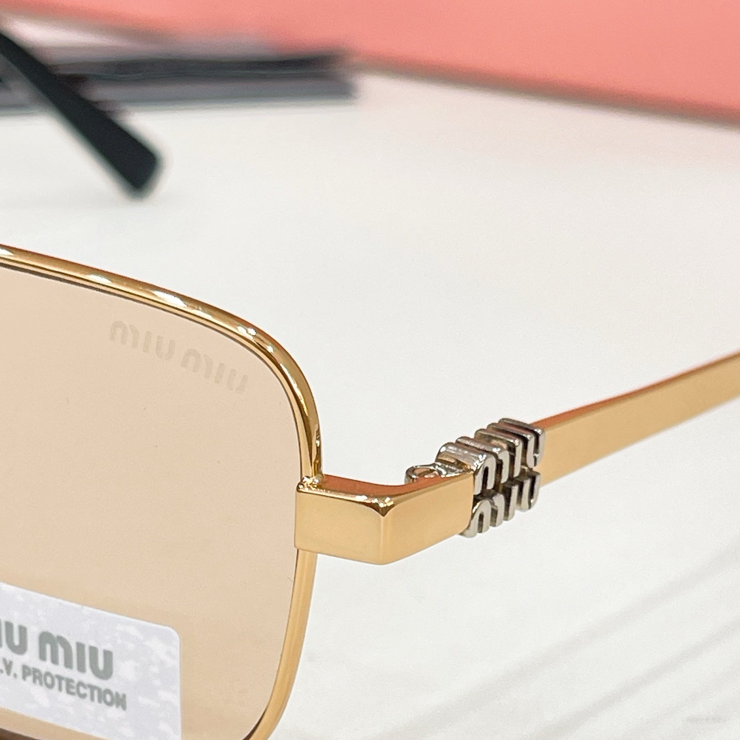 MiuMiu gold-tone eyeglass frame close-up with engraved hinge and logo temple detail