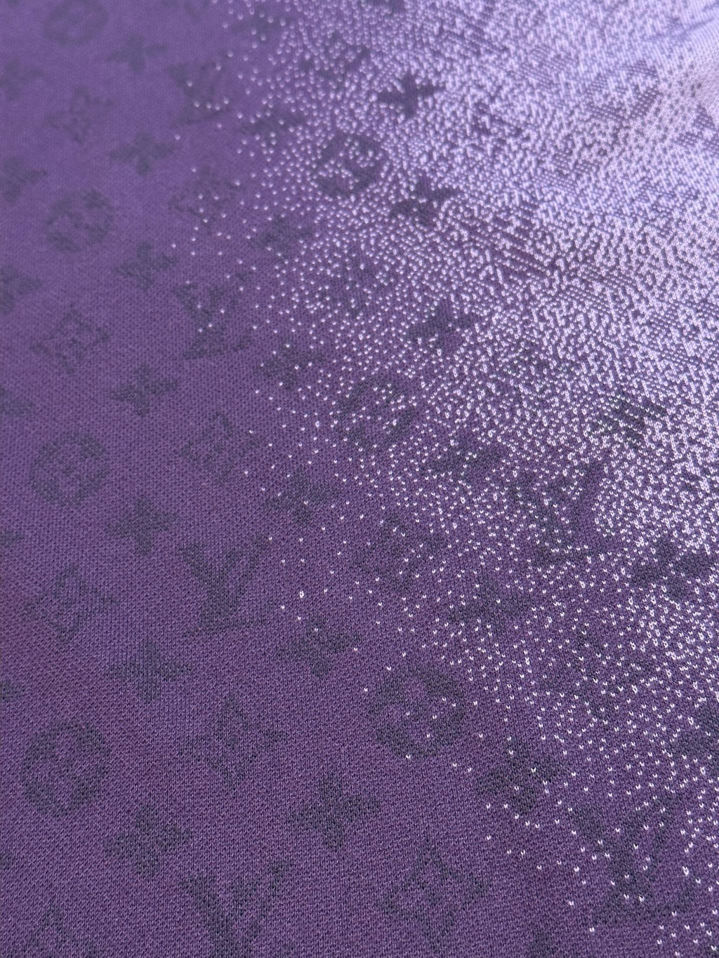 Purple T-shirt fabric close-up with dense textured graphic dots and pattern