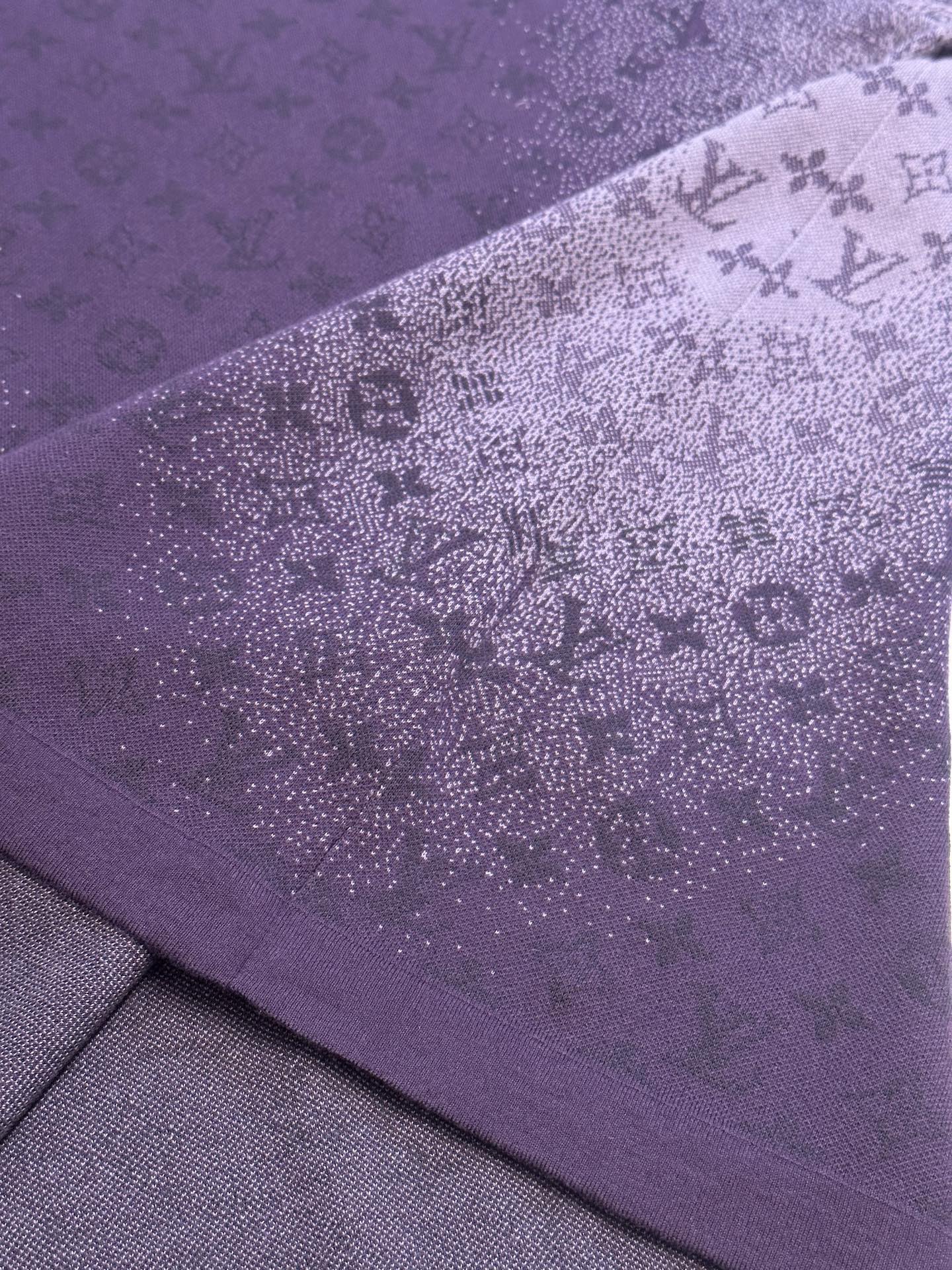 Purple T-shirt side fabric close-up with textured allover graphic print
