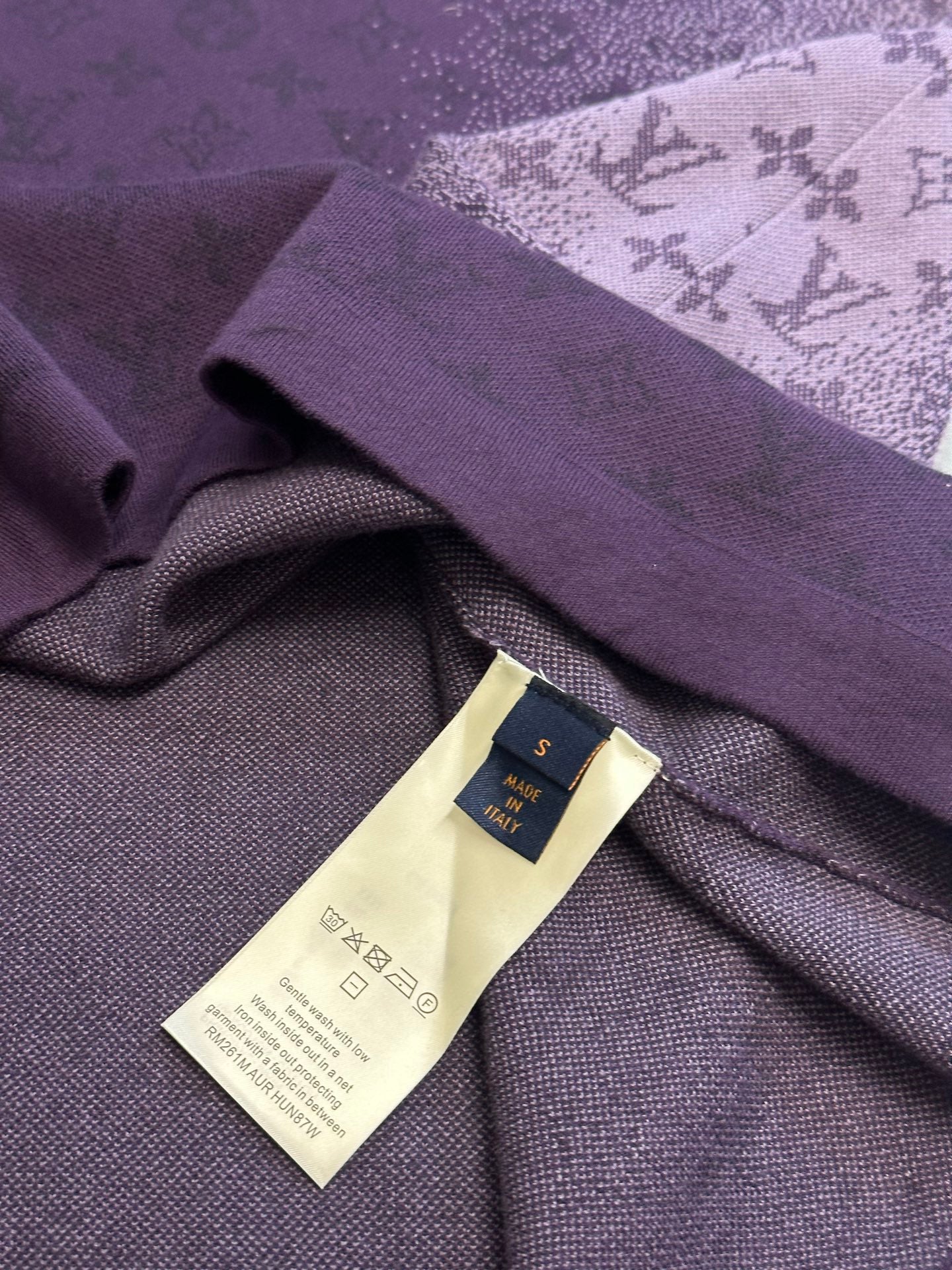 Purple T-shirt detail with woven brand label and care tag on inner fabric