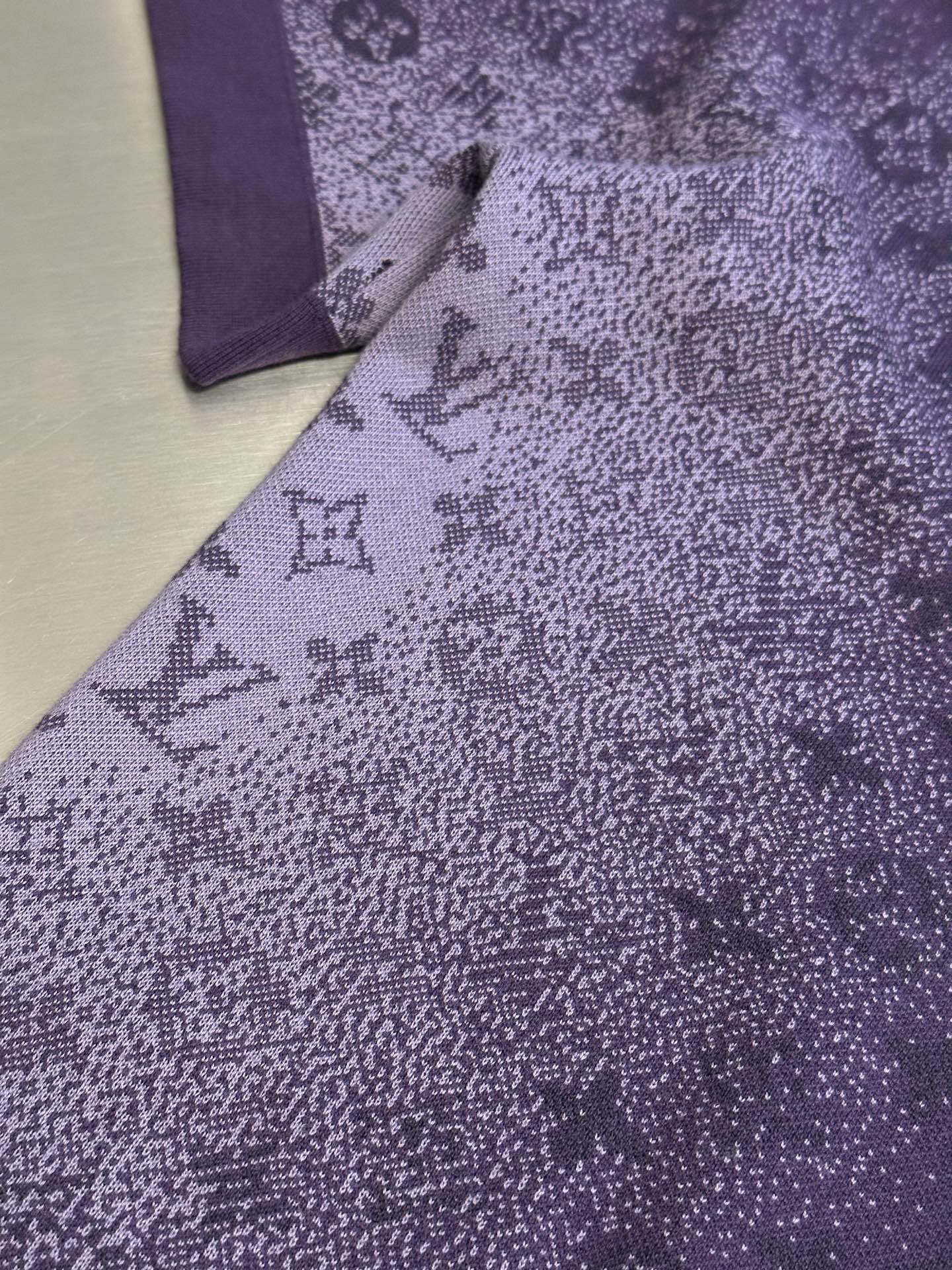 Purple T-shirt fabric with textured allover graphic print, close-up