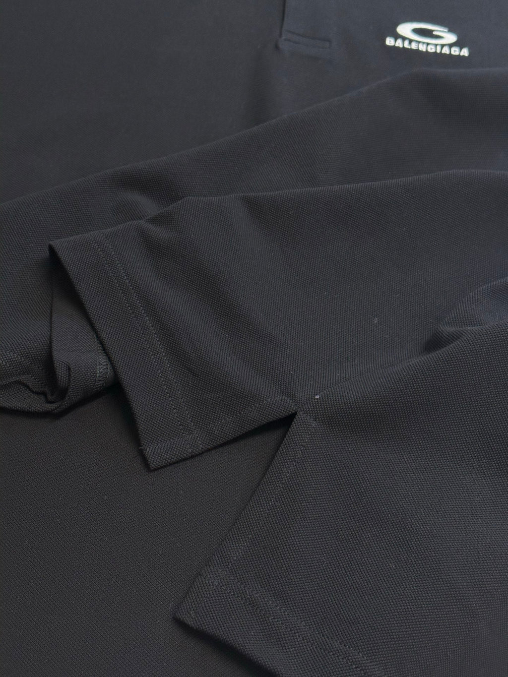 Balenciaga dark polo shirt fabric close-up, textured weave and stitched edge