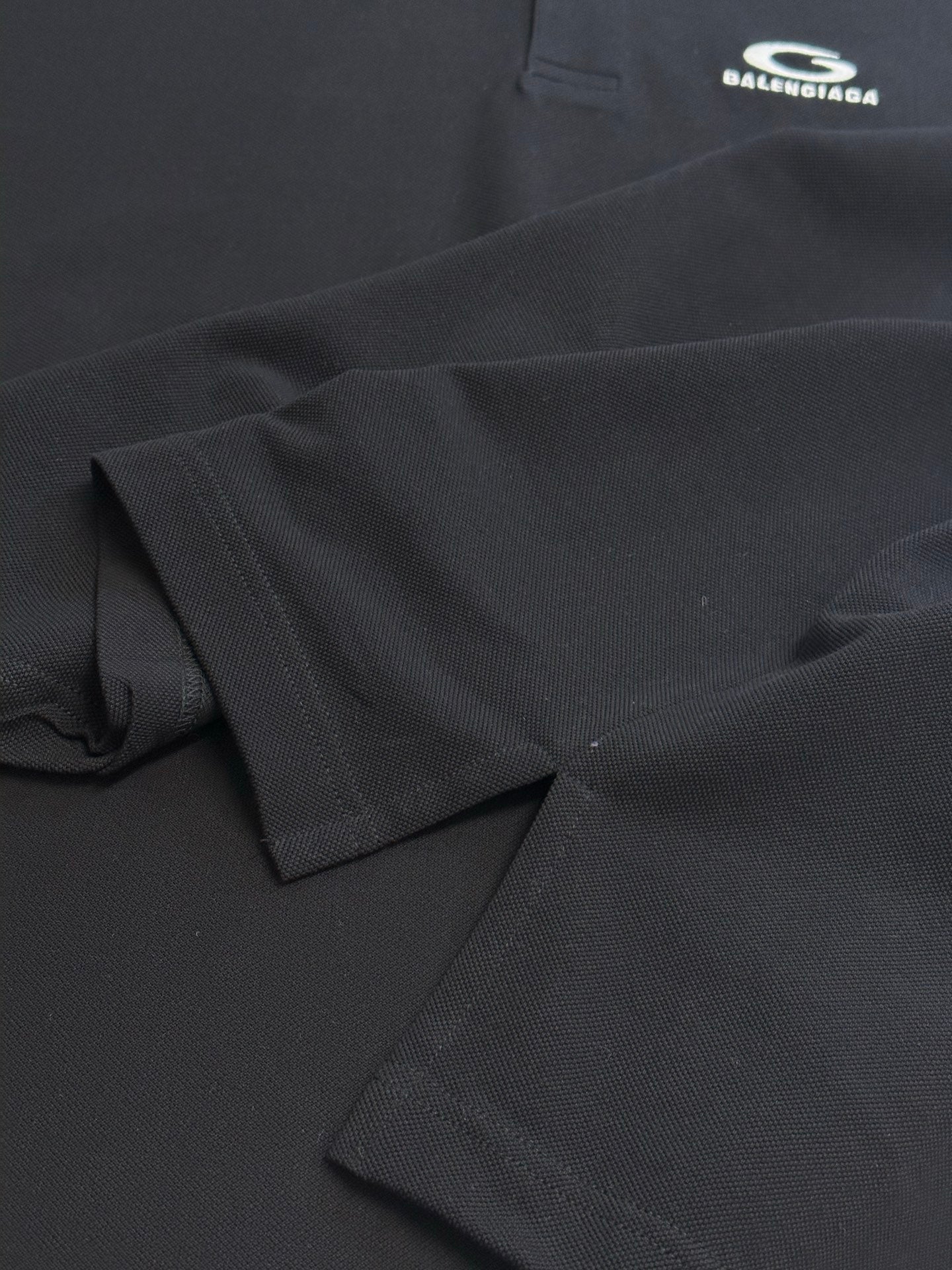 Balenciaga dark polo shirt fabric close-up, textured weave and stitched edge