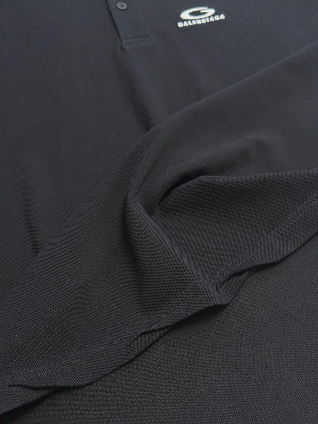 Balenciaga dark polo shirt fabric detail with stitched seam and drape