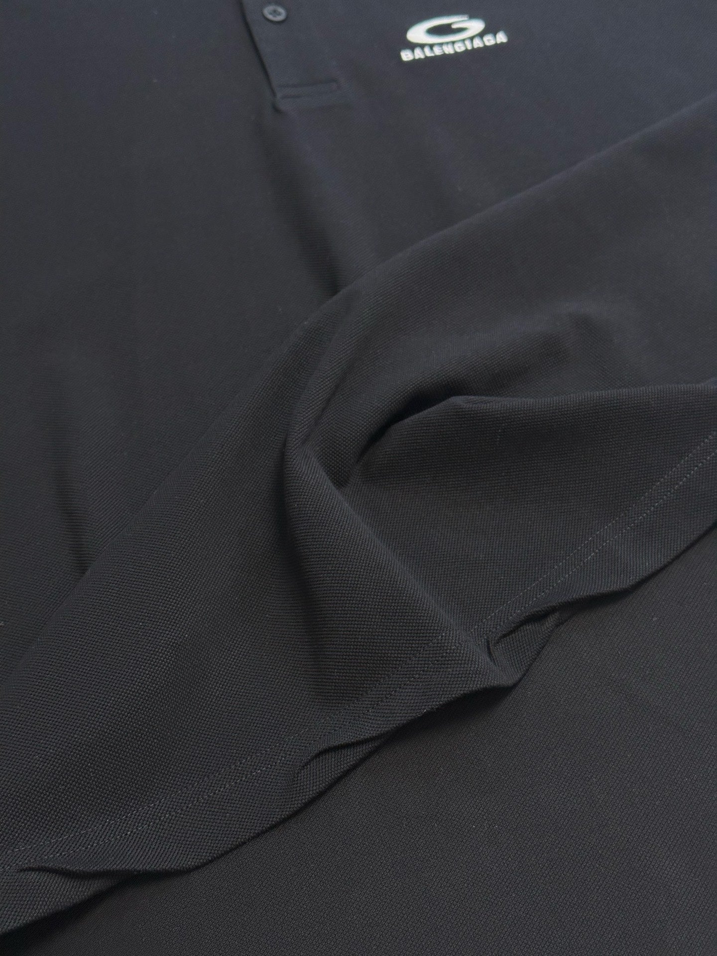 Balenciaga dark polo shirt fabric detail with stitched seam and drape