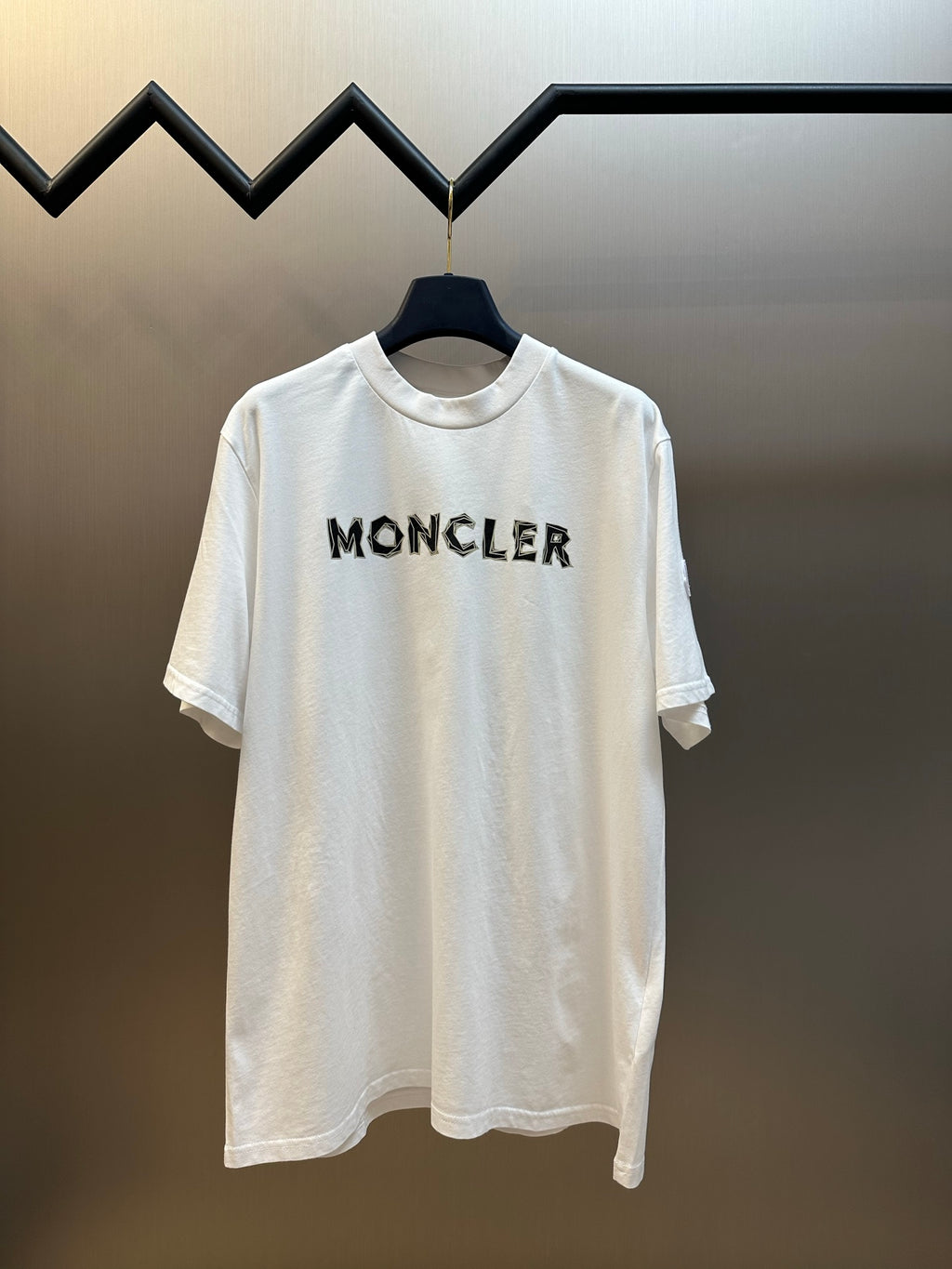 White Moncler short-sleeve T-shirt with black logo lettering at chest.