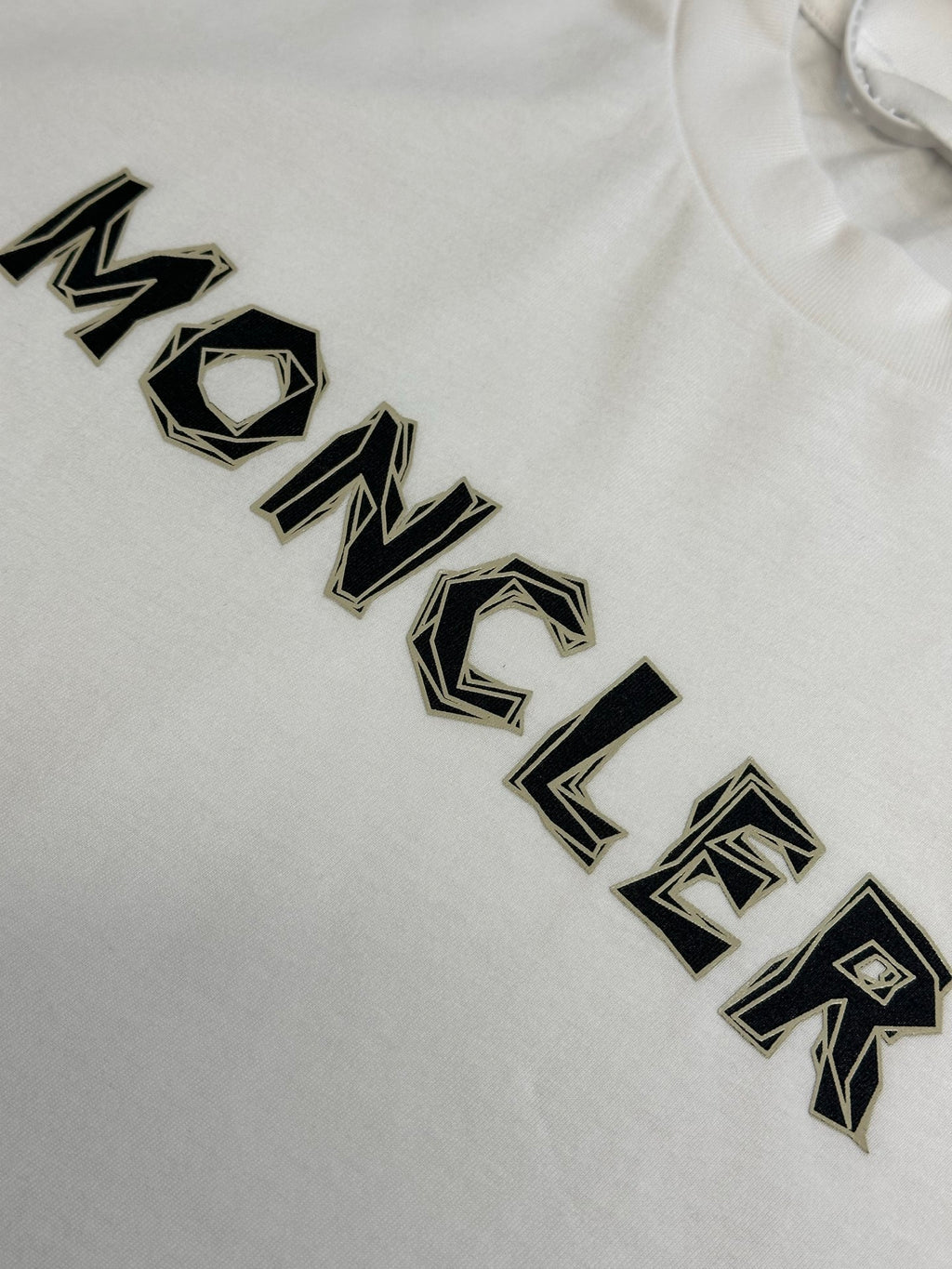 White Moncler T-shirt with black embroidered-style logo lettering close-up.