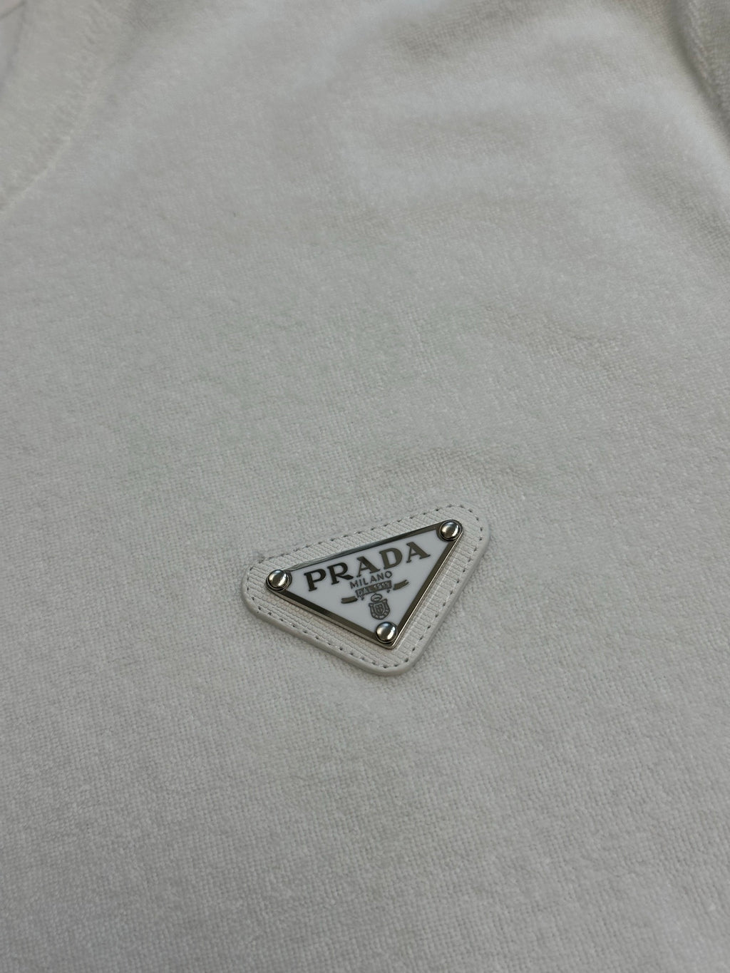 Prada triangular logo patch on white T-shirt fabric