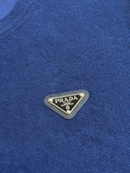 Prada triangular logo patch on blue T-shirt fabric.
