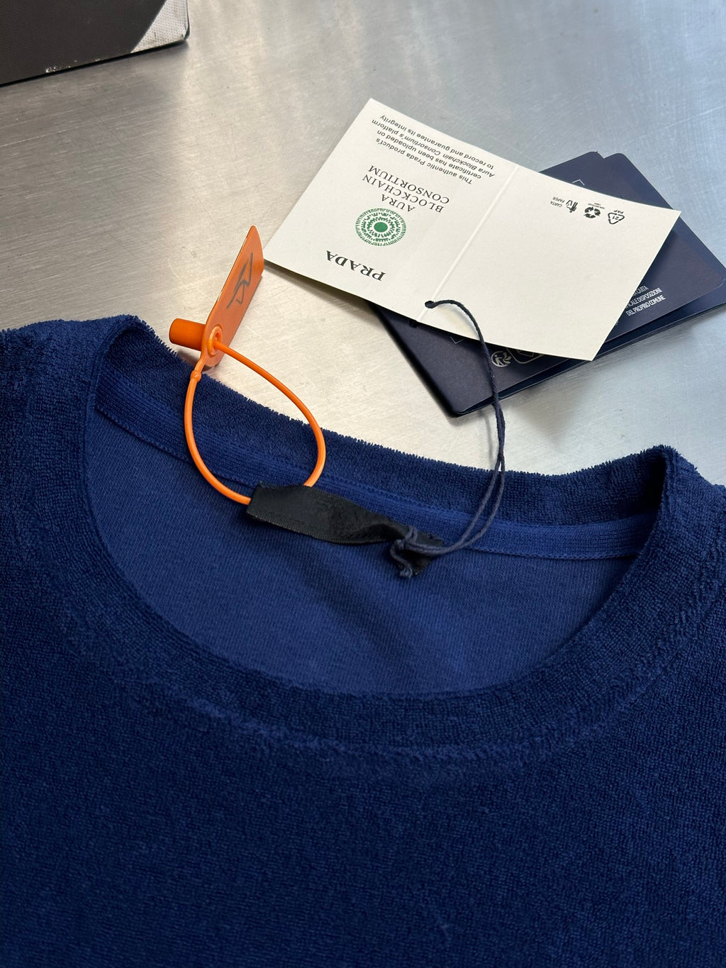 Prada blue T-shirt neckline, orange drawstring and care tags attached.