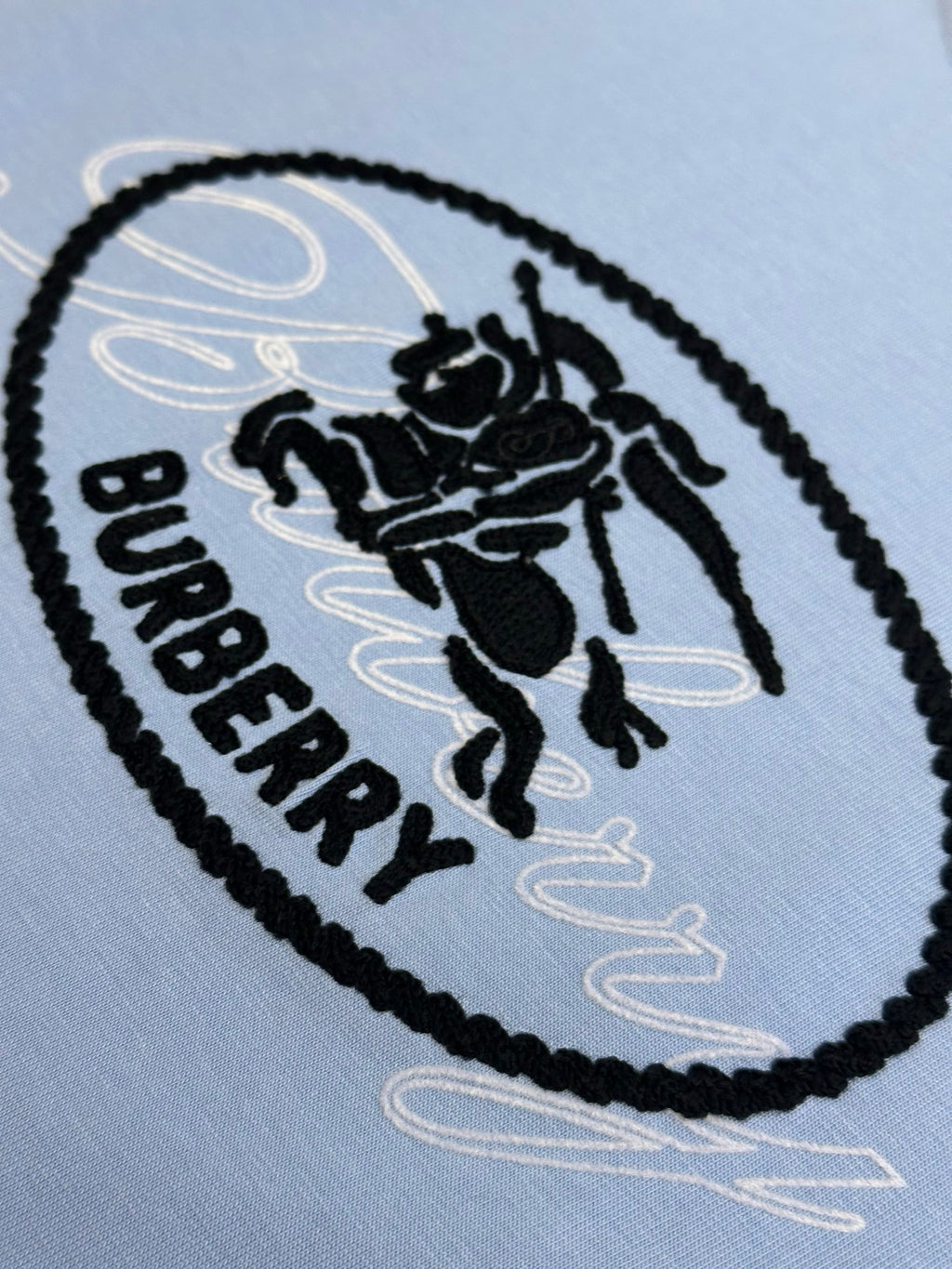Light blue T-shirt close-up of oval Burberry logo patch