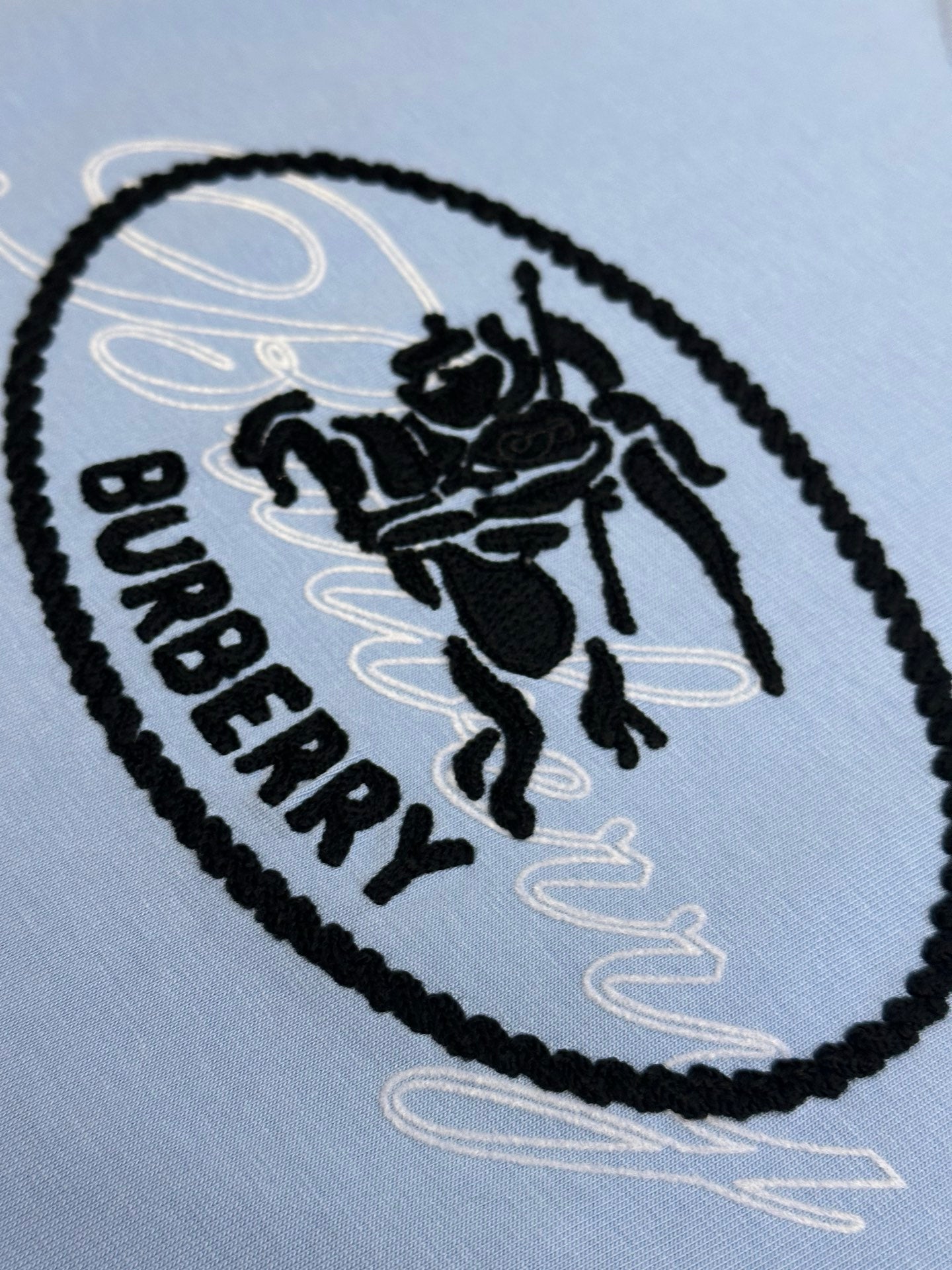 Light blue T-shirt close-up of oval Burberry logo patch