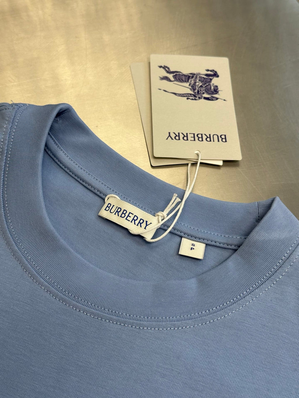 Light blue crewneck T-shirt collar with Burberry label and hanging tag