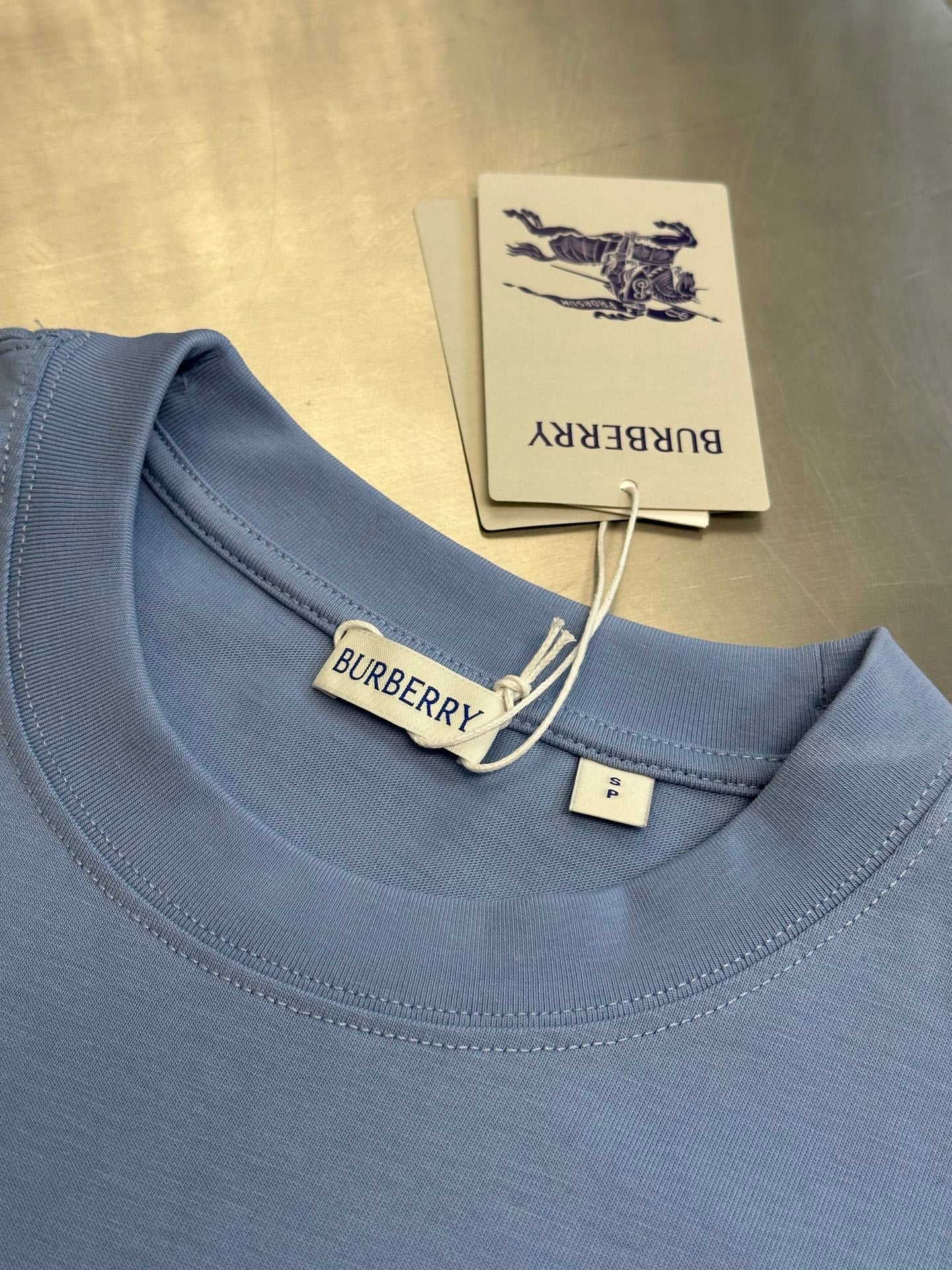 Light blue crewneck T-shirt collar with Burberry label and hanging tag