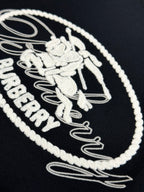 Close-up of white embroidered Burberry oval logo on black T-shirt