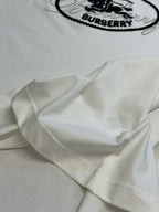 White T-shirt sleeve close-up with part of the black oval Burberry logo