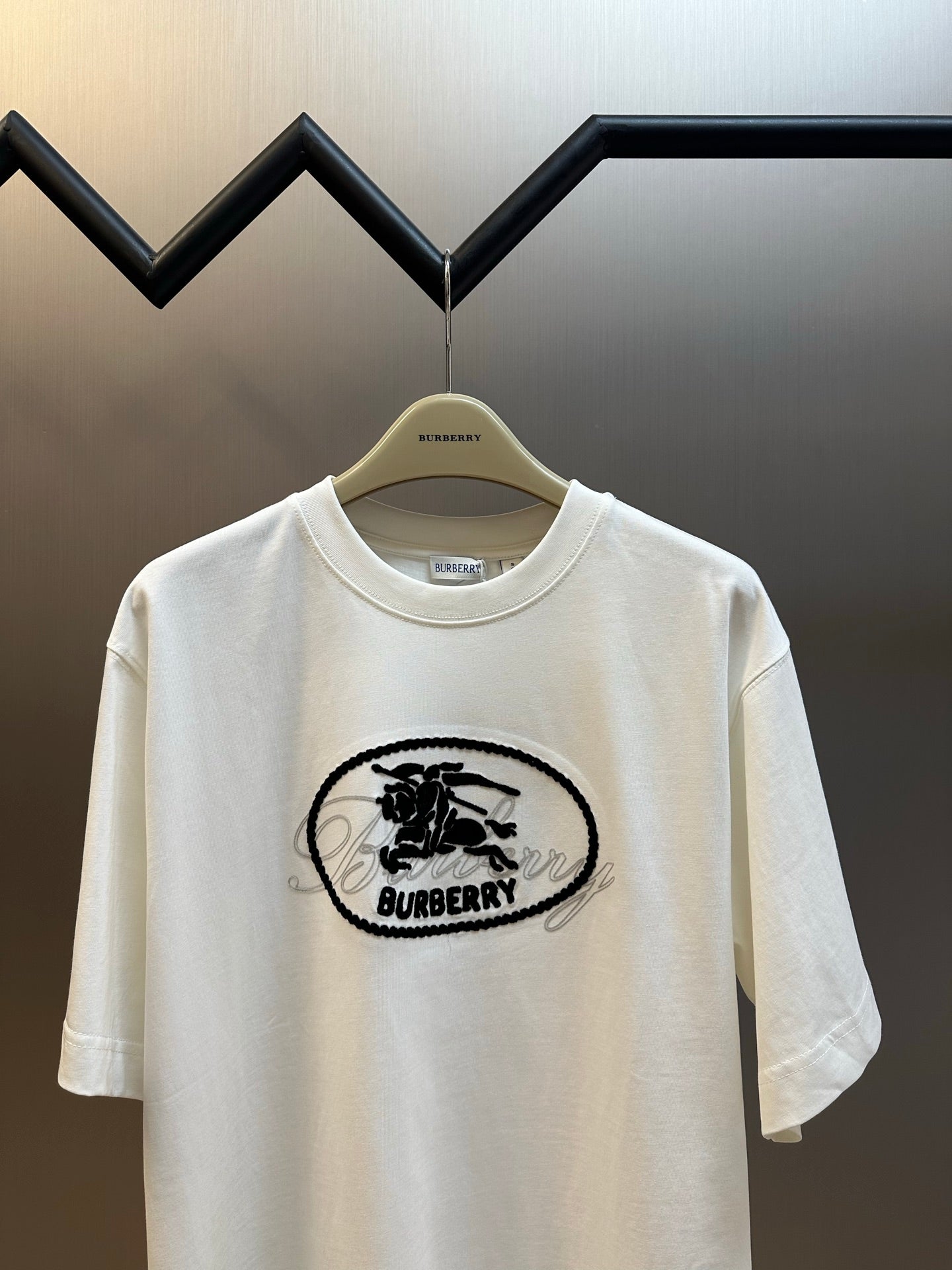 White long-sleeve T-shirt with black oval Burberry logo graphic at center chest