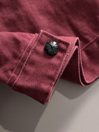 Maroon denim jacket sleeve with dark decorative snap and folded cuff detail