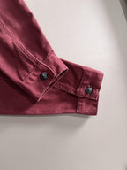 Maroon denim jacket sleeve cuff with dark snap buttons and stitched details