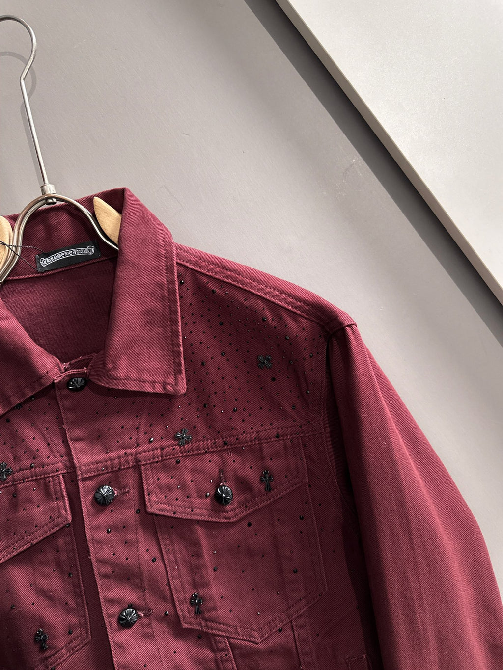 Maroon denim jacket close-up on hanger, point collar, snap front, small stud accents