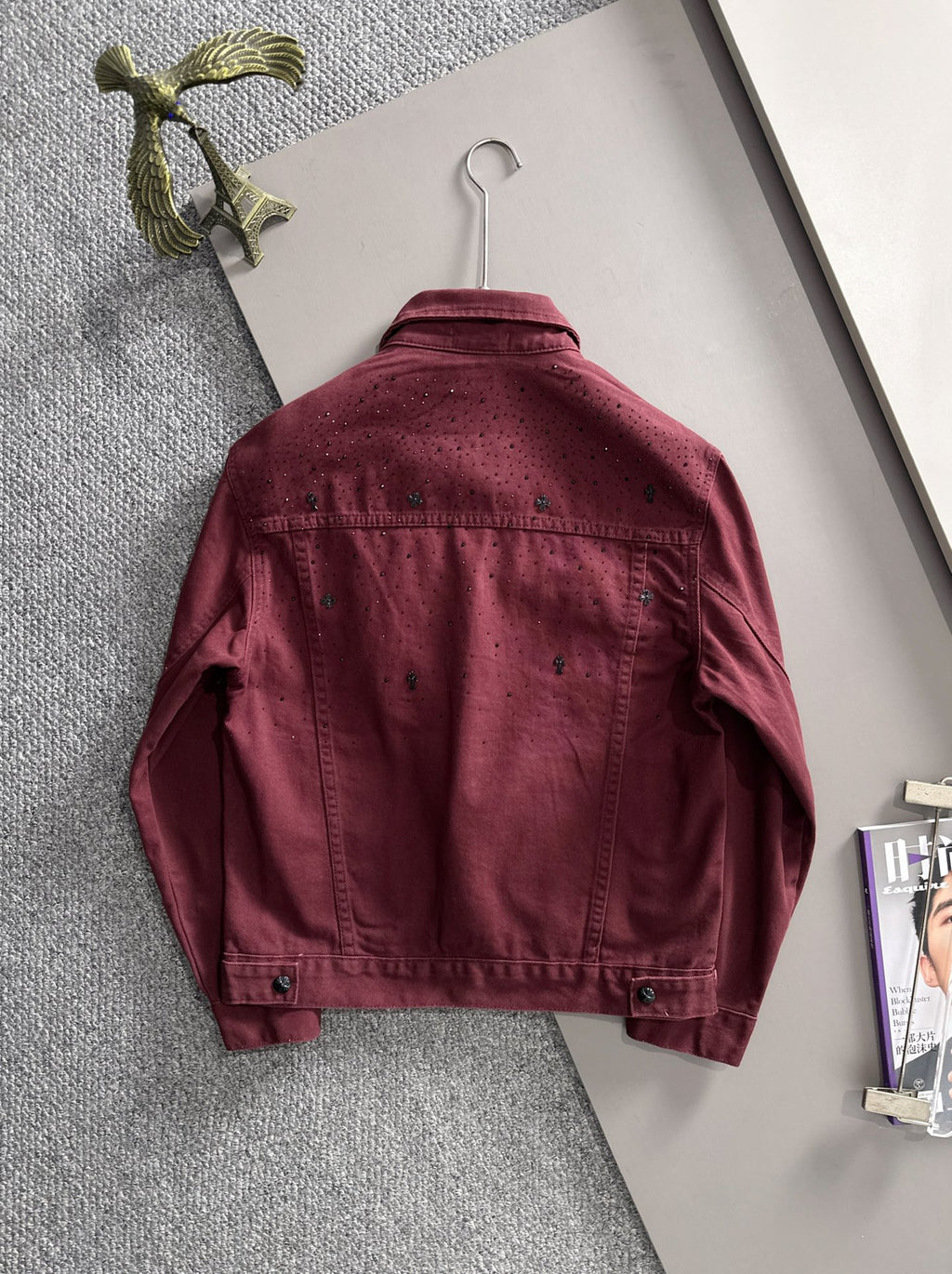 Maroon denim jacket back on hanger, long sleeves, snap buttons, studded texture